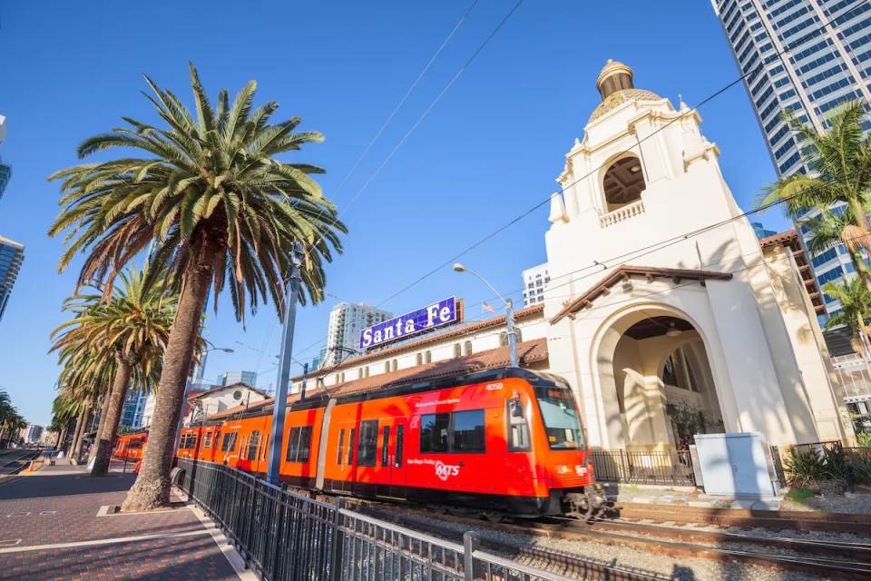 Red San Diego trolley in front of 1915 Neo-Spanish building at Santa Fe Depot in downtown San Diego, California.